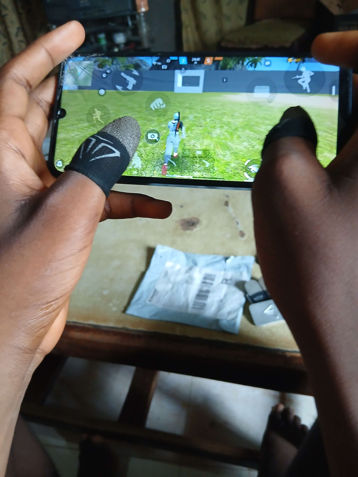Hands using Zuky hub elite mobile gaming thumb sleeves while playing a game on a smartphone.